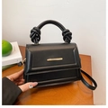 Detail view of black trapezoid crossbody bag with knotted handle and gold metal clasp - Black