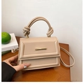 Modern apricot small square bag with double knot handle and gold hardware on table - Khaki