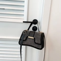 Fashionable black crossbody bag with silver studs and gold hardware on white door - Black