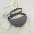 Minimalist dark grey nylon crescent bag with adjustable strap on white blazer - Gray