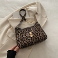 Sac bandoulière léopard avec chaîne dorée et fermoir pivotant sur un blazer beige - Marron