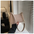 Detail of pink faux crocodile texture underarm bag with gold chain strap held by model - Khaki