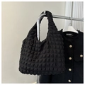 Close-up of black bubble textured tote bag hanging with a tweed jacket on white background - Black