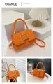 Detail view of an orange embossed crossbody bag with golden buckle and strap details - Orange