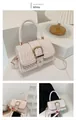 Detail of white quilted crossbody bag showing embossed texture and gold metal buckle - White
