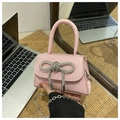 Pink mini crossbody bag featuring a large rhinestone bow and silver chain strap details - Pink