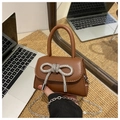 Close-up of brown mini crossbody bag featuring a sparkling rhinestone bow and silver chain - Brown