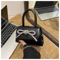 Close-up of a mini black leather bag with a sparkling silver rhinestone bow detail - Black