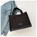 Detail of black quilted tote bag featuring leather bottom and Fashion Bag label - Black