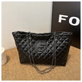 Macro shot of black quilted faux leather texture with chain strap on a chic tote bag - Black