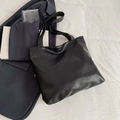 Minimalistische schwarze PU-Leder-Einkaufstasche mit breiten Trägern auf weißem Betttuch - Schwarz