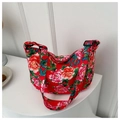 Detail showing the red floral peony pattern and adjustable strap on the crescent dumpling bag - Red