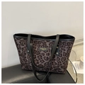 Dettaglio della borsa leopardata con targhetta logo in pelle nera e rivetti metallici - Marrone