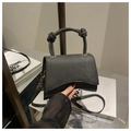 Detail der schwarzen Trapez-Handtasche mit Knotengriff und matter Textur - Schwarz