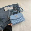 Light blue crossbody bag with wave quilting and butterfly clasp on denim background - Blue