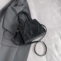 Black crinkled leather tote bag with round handles and detachable strap on a blazer - Black