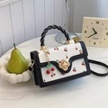 White mini square bag with red cherry prints and black braided handle on a marble table - Black