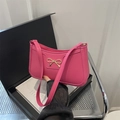 Fuchsia pink leather baguette bag featuring a gold bow metallic buckle on a gift box - Rose Pink
