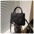 Detail of black crossbody bag with embossed star pattern and pale gold hardware accents - Black