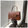 Detalle de bolso marrón con textura de cuero, botón redondo y asa superior elegante - Marrón