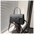 Detalle de bolso negro minimalista mostrando textura de grano y hebilla de botón redonda - Negro