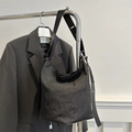 Elegante borsa hobo in denim nero con tracolla in pelle appesa a un rack - Nero