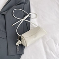Chic beige lychee textured leather crossbody bag with a floral pendant and drawstring strap - White