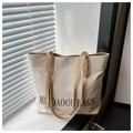Dettaglio della borsa tote in tela con stampa di lettere marroni e lunghe spalline eleganti - Cachi