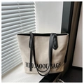 Dettaglio borsa tote in tela beige con scritte MIHOAOOUI nere e tracolle in pelle - Bianco e Nero