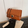 Brown quilted crossbody bag with golden clover clasp and chain strap held by hand - Brown
