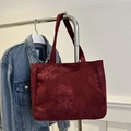 Retro burgundy corduroy tote bag with floral embroidery hanging on a metal rack - Red