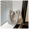 Detalle del bolso tipo cubo gris plata con cordón, textura plisada y lazo metálico fino - Plateado