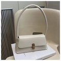 Detail of elegant cream shoulder bag with golden twist lock on a stack of books - White