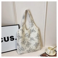 Dettaglio ricamo farfalla su borsa tote in tessuto bianco con texture - Grigio