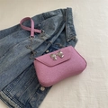 Pink glitter crossbody bag with silver bow accent on blue denim background - Pink