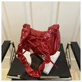 Detail of red patent leather crescent bag with bow decoration and pleated edges - Red