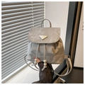 Detalle de mini mochila gris con cierre de cordón y placa metálica con logo decorativo - Plateado