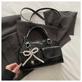 Détail du sac Boston en cuir verni noir avec nœud en perles et pendentif cœur argenté - Noir