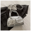 Détail du sac Boston argenté avec nœud perlé et breloque cœur sur une veste noire - Argenté