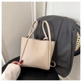 Detail van beige leren tote bag met lychee patroon en gouden TOTE BAG tekst - Donker kaki