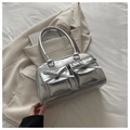 Dettaglio della borsa bowling argento metallizzato con fiocchi e tasche su un blazer - Argento