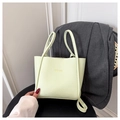 Detailopname van mintgroene leren shopper met kiezeltextuur en gouden tekst in de hand - Groen