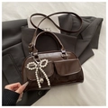 Detail of a dark brown glossy Boston bag with pearl bow and heart metal pendant - Coffee