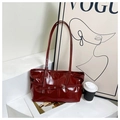 Close-up of deep red glossy patent leather shoulder bag with buckle strap detail - Red
