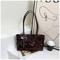 Deep brown patent leather tote bag with decorative buckle on a minimalist display - Brown