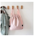 Zaino a secchiello rosa con coulisse appeso al gancio con giacca di jeans e cuffie - Rosa