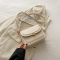 Piccola borsa a tracolla bianco crema con chiusura dorata su una giacca beige - Bianco