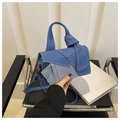 Detailed close-up of blue denim patchwork handbag with contrast white stitching details - Blue