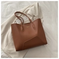Macro detail of brown leather tote bag showing fine stitching and protective metal studs - Brown