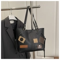 Detalle de bolso tote vintage con parches decorativos y textura de cuero elegante - Negro